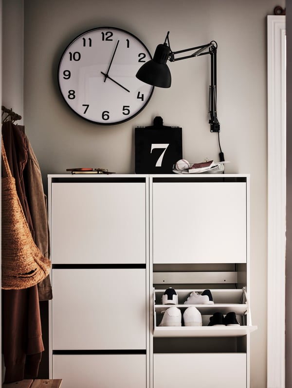 Zapatero BISSA blanco con 3 compartimentos, con una lámpara de escritorio TERTIAL y un reloj de pared PLUTTIS.