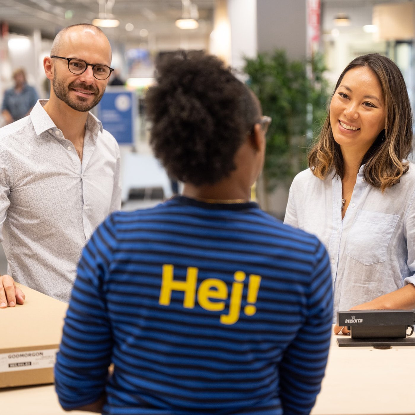 Collaborateur IKEA accueillant deux clients dans un magasin.