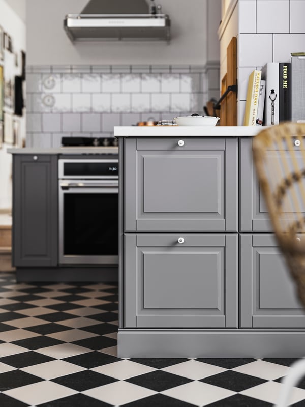 A kitchen with gray BODBYN fronts and a white HAVSEN sink bowl with visible front leading into a hallway with more cabinets.