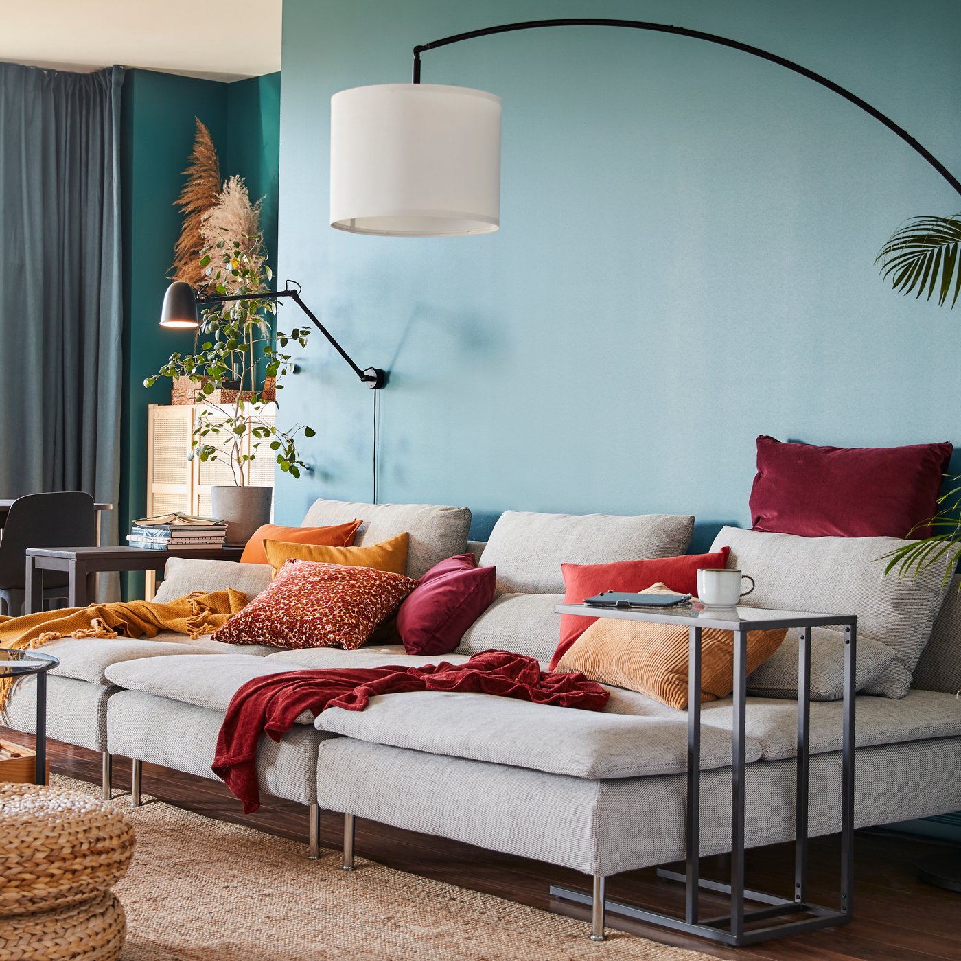 A SKURUP work/wall lamp is mounted on the wall above three SÖDERHAMN chaise longues in a colourful living room.