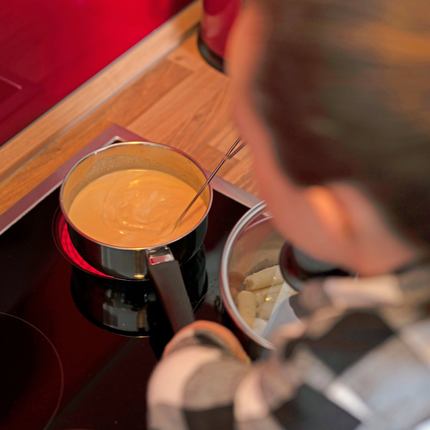 A woman stirs some ALLEMANSRÄTTEN cream sauce in a pot on a stove.