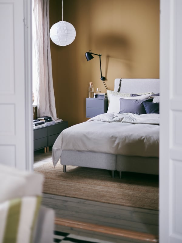 A glimpse into a warm and inviting bedroom with the DUNVIK bed and REGOLIT pendant lamp shade made from paper.