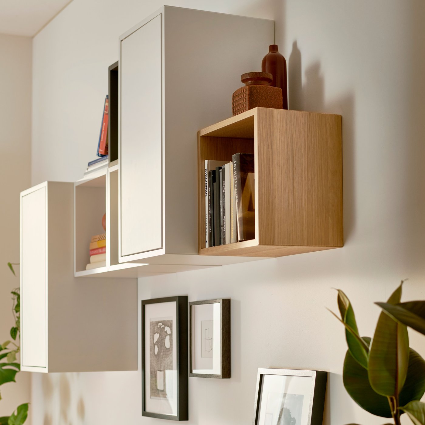 Different EKET cabinets, including a white stained oak effect EKET cabinet, and two works of art are mounted on a wall.