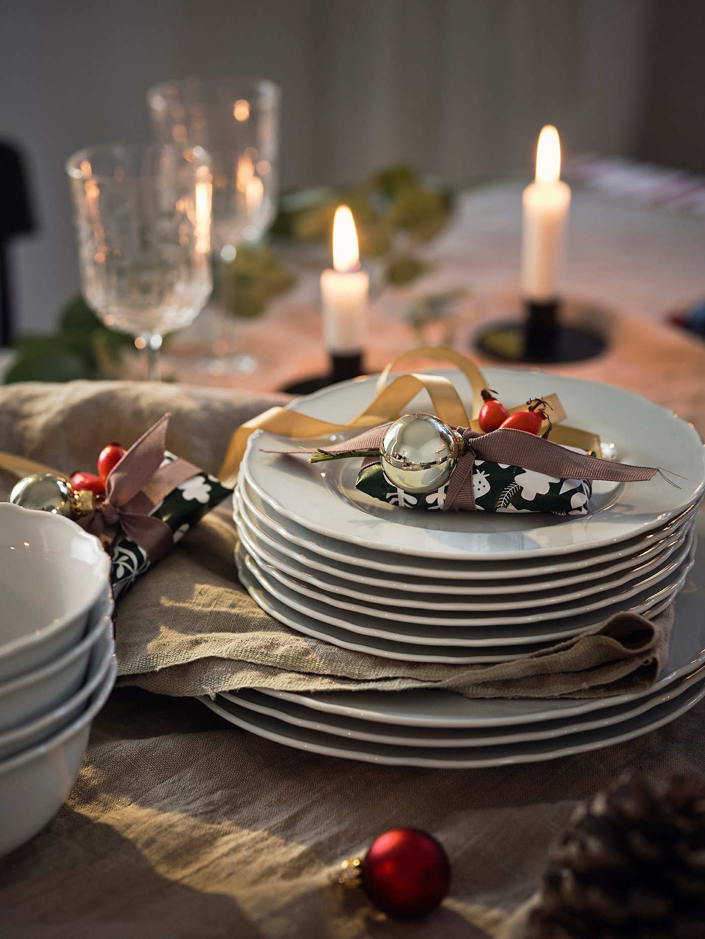 Des assiettes blanches empilées sur une table de Noël avec une nappe grise.