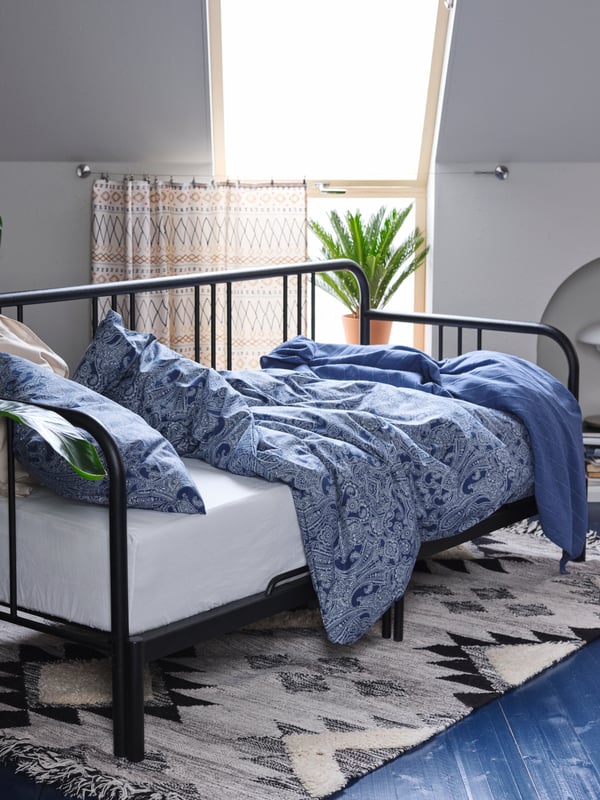 Katil siang FYRESDAL dengan duvet dan bantal di dalam linen katil JÄTTEVALLMO berwarna biru/putih diletakkan pada ambal TANNISBY.