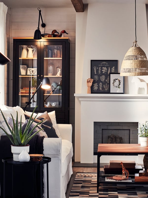 A white sofa and black wooden bookcase are illuminated by a black SKURUP work/wall lamp and matching floor lamps.