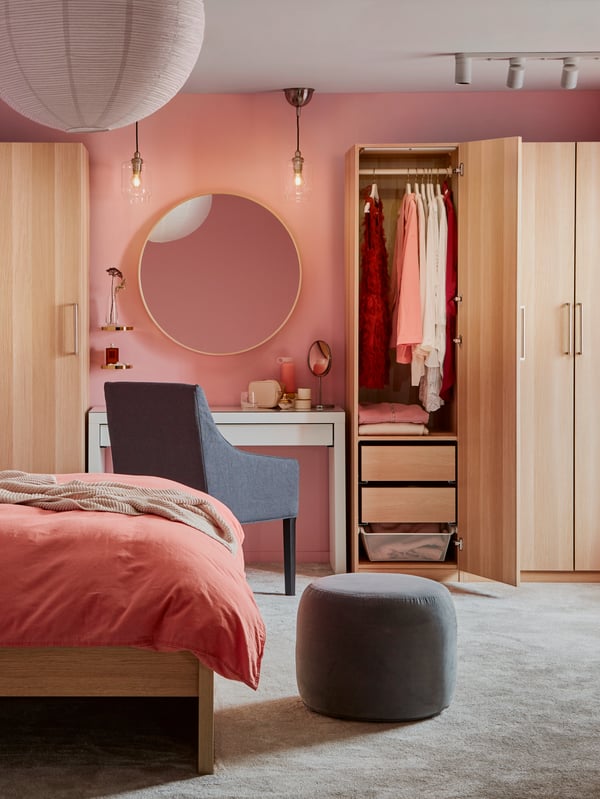 Pink bedroom with wooden wardrobes and a white MALM dressing table between the wardrobes.