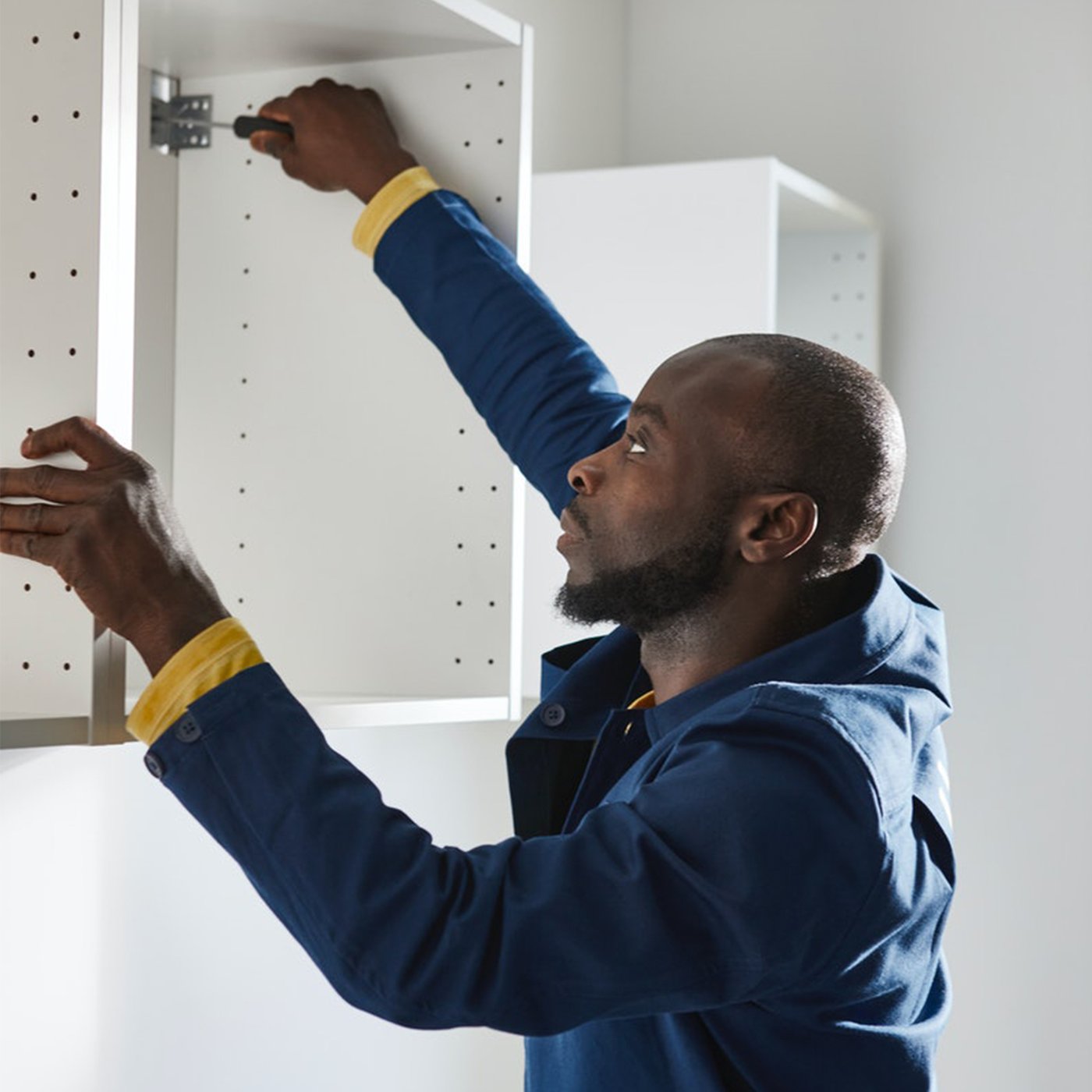 An IKEA employee assembles a white kitchen cabinet.