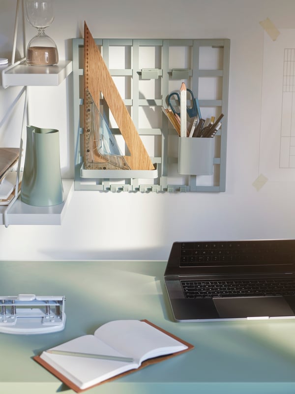 A SNICKRA storage board holds pens, pencils and a ruler. Other desk items sit on a pair of BERGSHULT/PERSHULT wall shelves.