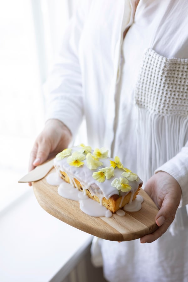 En saftig citronkage og pyntet med en generøs mængde glasur og økologiske stedmoderblomster.