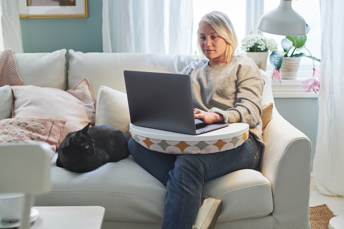 Eine Frau sitzt mit einem Laptop auf einem Sofa.