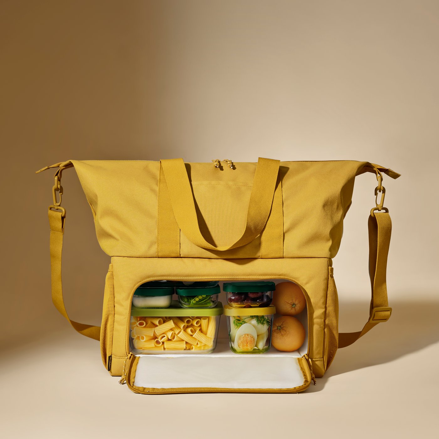 A yellow KLOTPIL cooling bag with two separate compartments is open and there are food containers with vegetables inside.