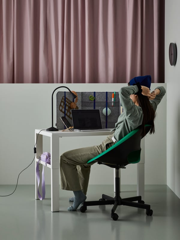A teen girl studies at a PÅHL desk at the tallest setting. She is in a ELDBERGET/MALSKÄR swivel chair, looking at a laptop.