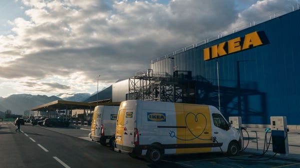 Dos vehículos eléctricos de transporte de IKEA en un punto de carga frente a una tienda IKEA en Suiza.