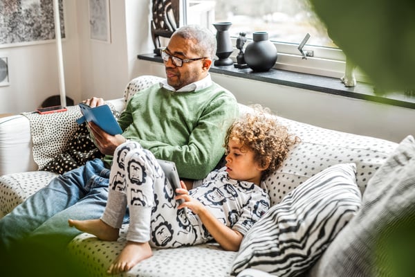 A father and son are lounging on a couch.