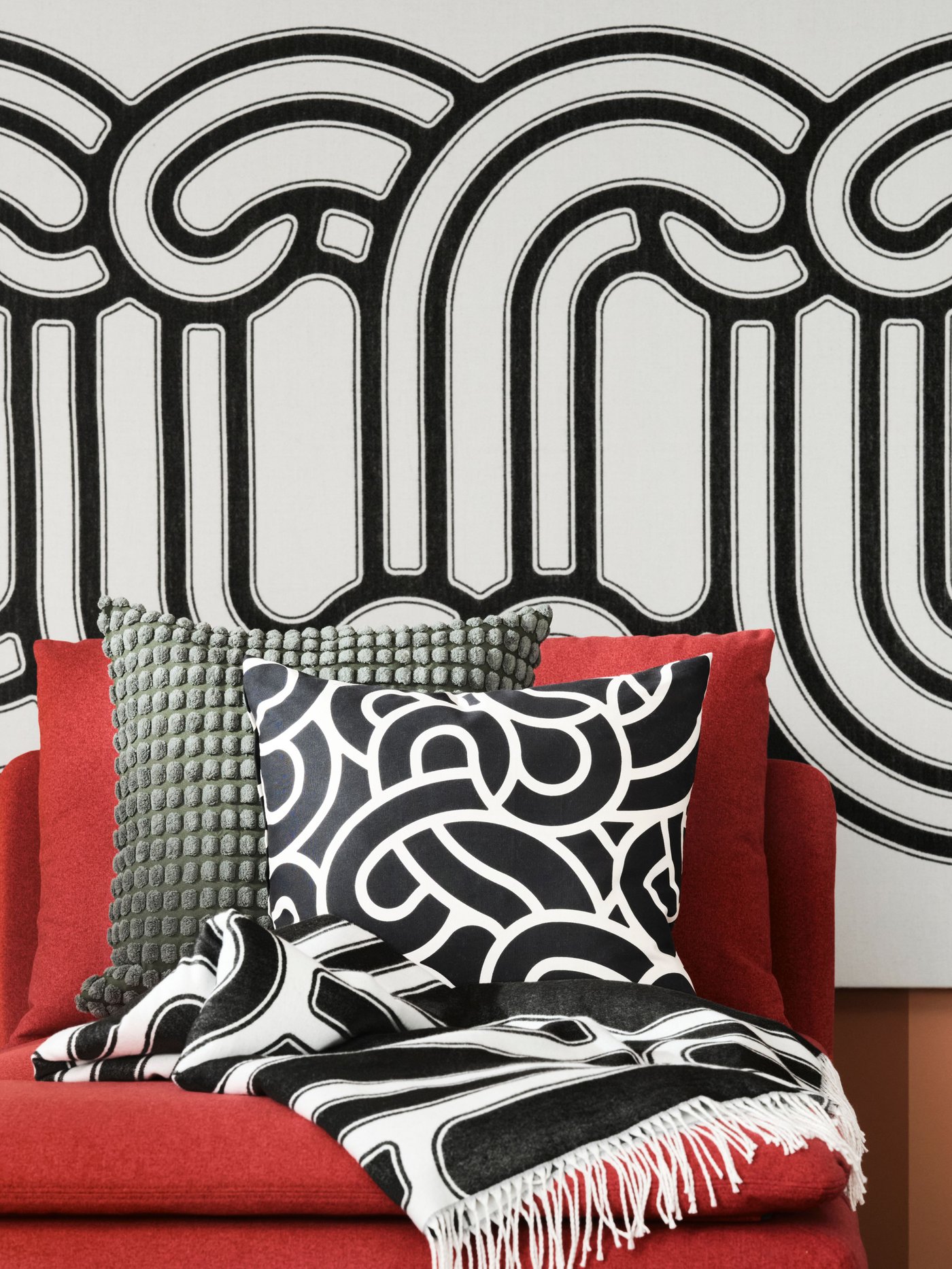 Bold and graphic cushions from SÖTRÖNN collection on a red SÖDERHAMN sofa.