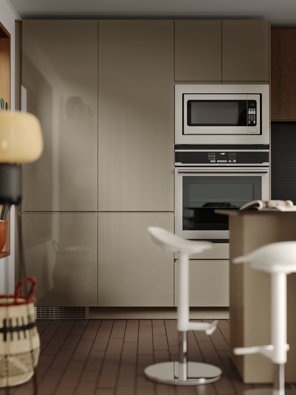 Les armoires de cuisine avec électroménagers encastrables dotées de façades VOXTORP gris-brun foncé brillant sont disposées de manière linéaire.