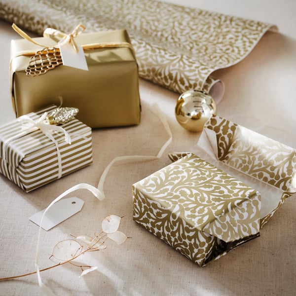 Des cadeaux emballés dans du papier cadeau doré et blanc, avec des décorations festives