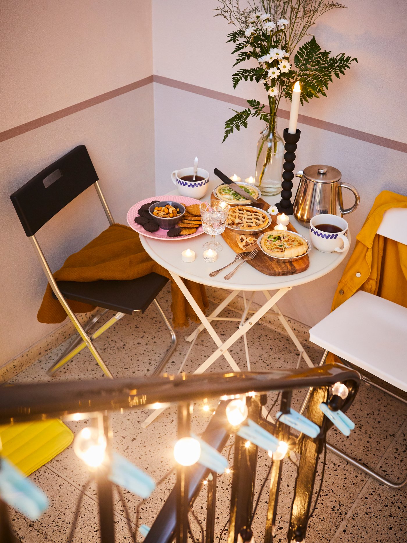 Un comedor pequeño al costado de una escalera con mesas y sillas plegables.