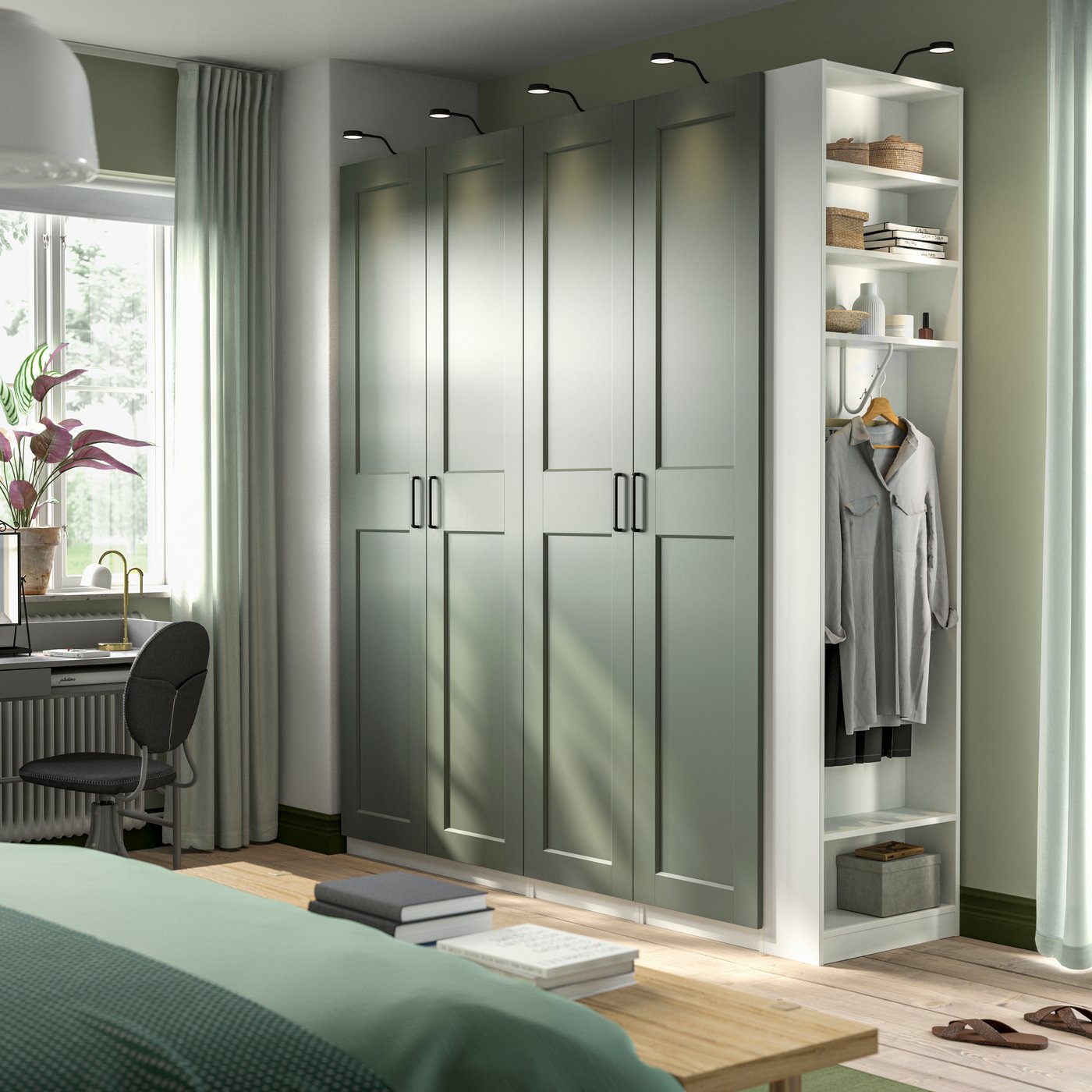 PAX Kleiderschrank mit graugrünen Fronten in einem hellen Schlafzimmer mit Teppich, Sitzmöbel und offenem Regalelement.