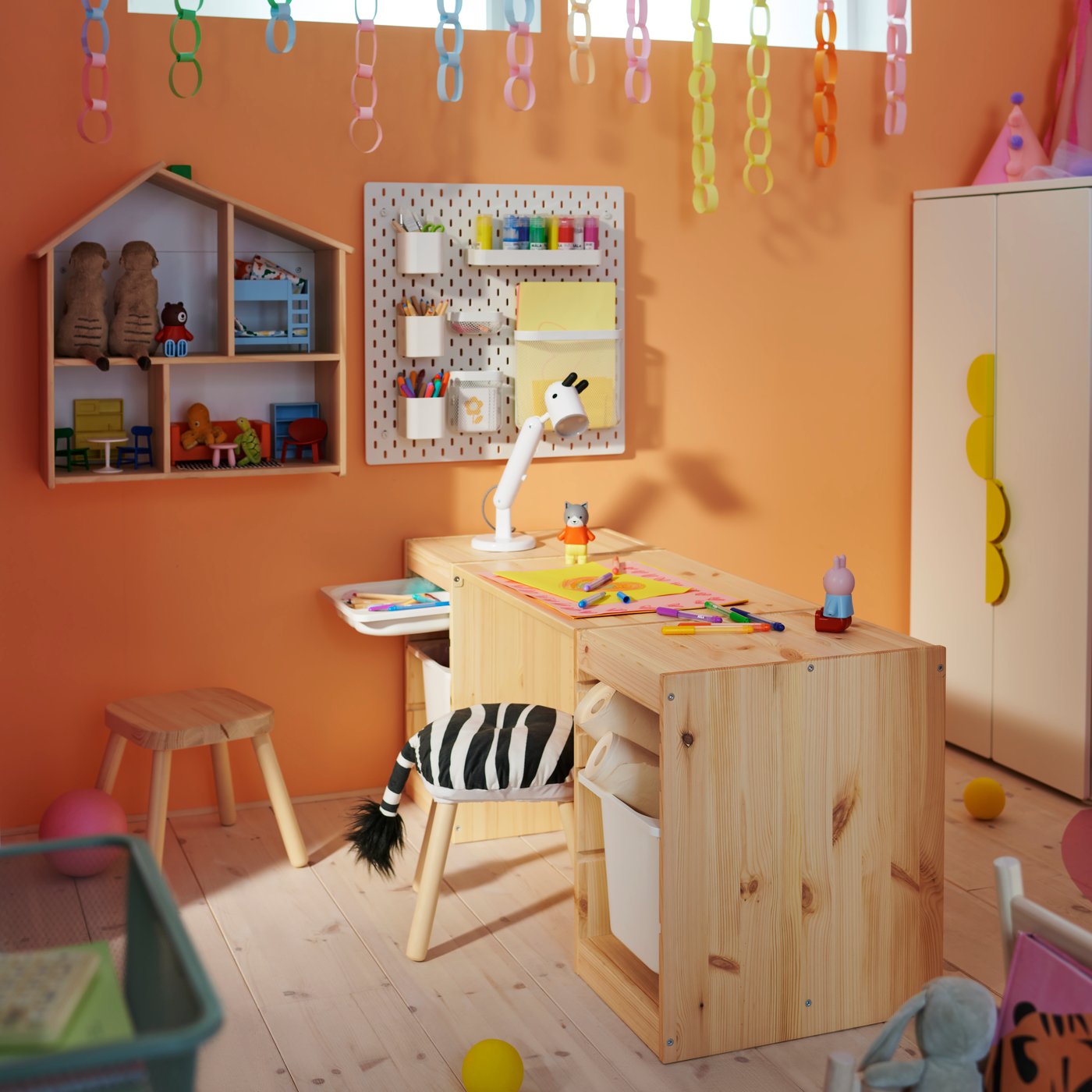 Two light white stained pine TROFAST frames with a tabletop make a desk in a children’s room with a FLISAT stool in front.
