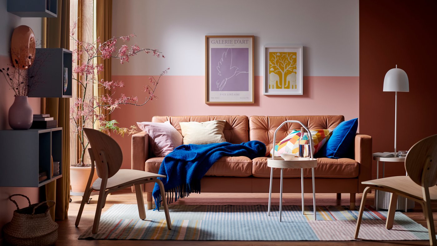 A LANDSKRONA sofa, with a blue KLIPPOXEL throw and extra cushions on it, and a BURVIK side table stand on a BUDDINGE rug.