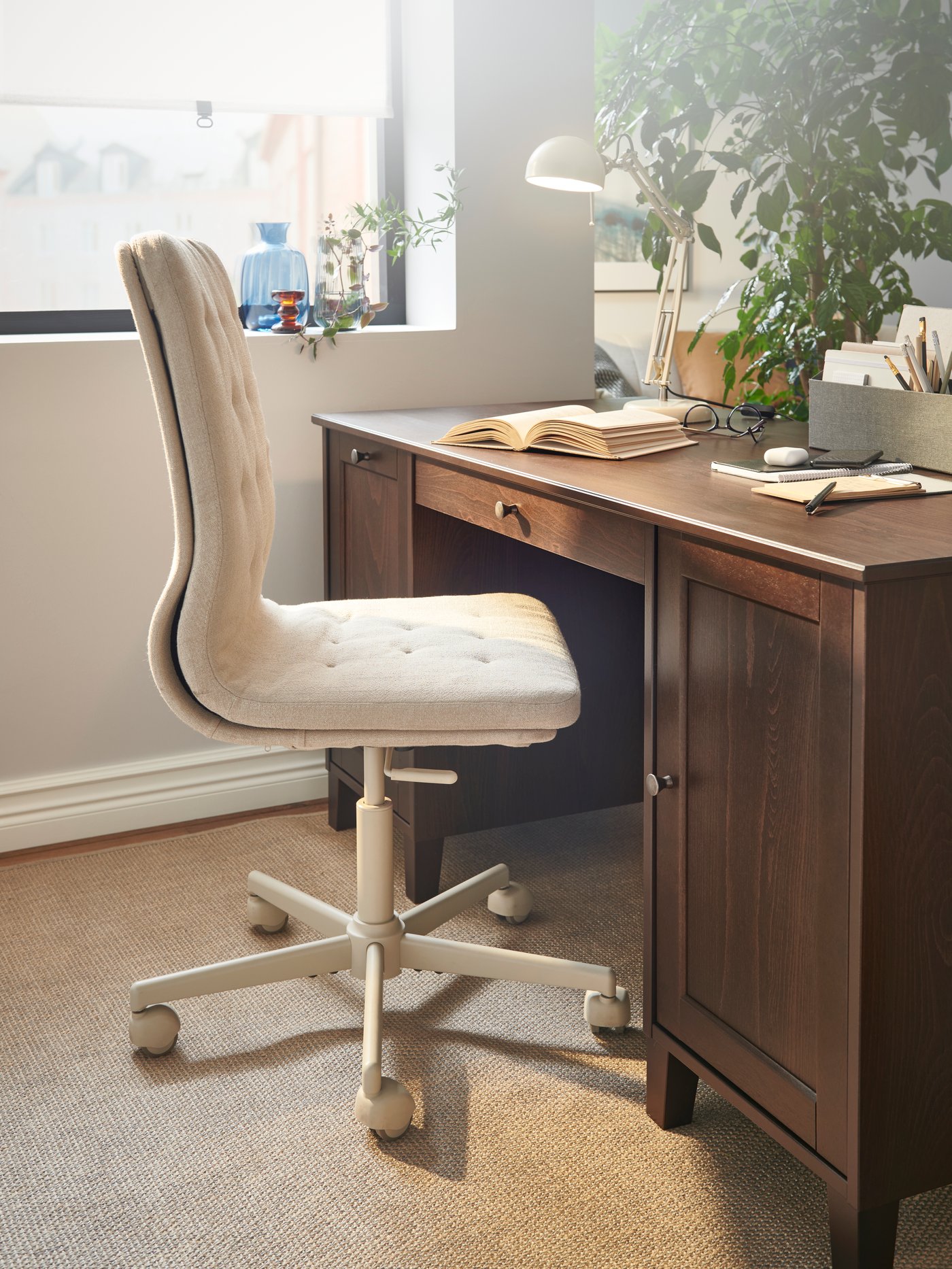 A workspace with a retro vibe with beige walls, dark wooden furniture and a MULLFJÄLLET conference chair with castors.