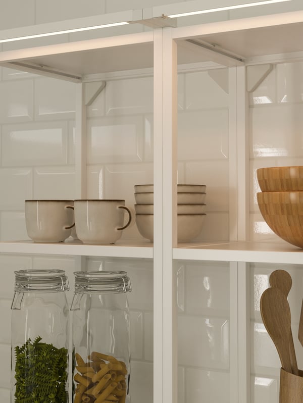 White open shelving units holding tableware, utensils and jars, lit by SKYDRAG LED lighting strips running across the top.