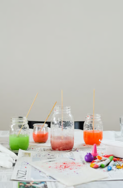 Grüne, orange und rosa Wachsfarbe in Glasbehältern, auf einem Tisch