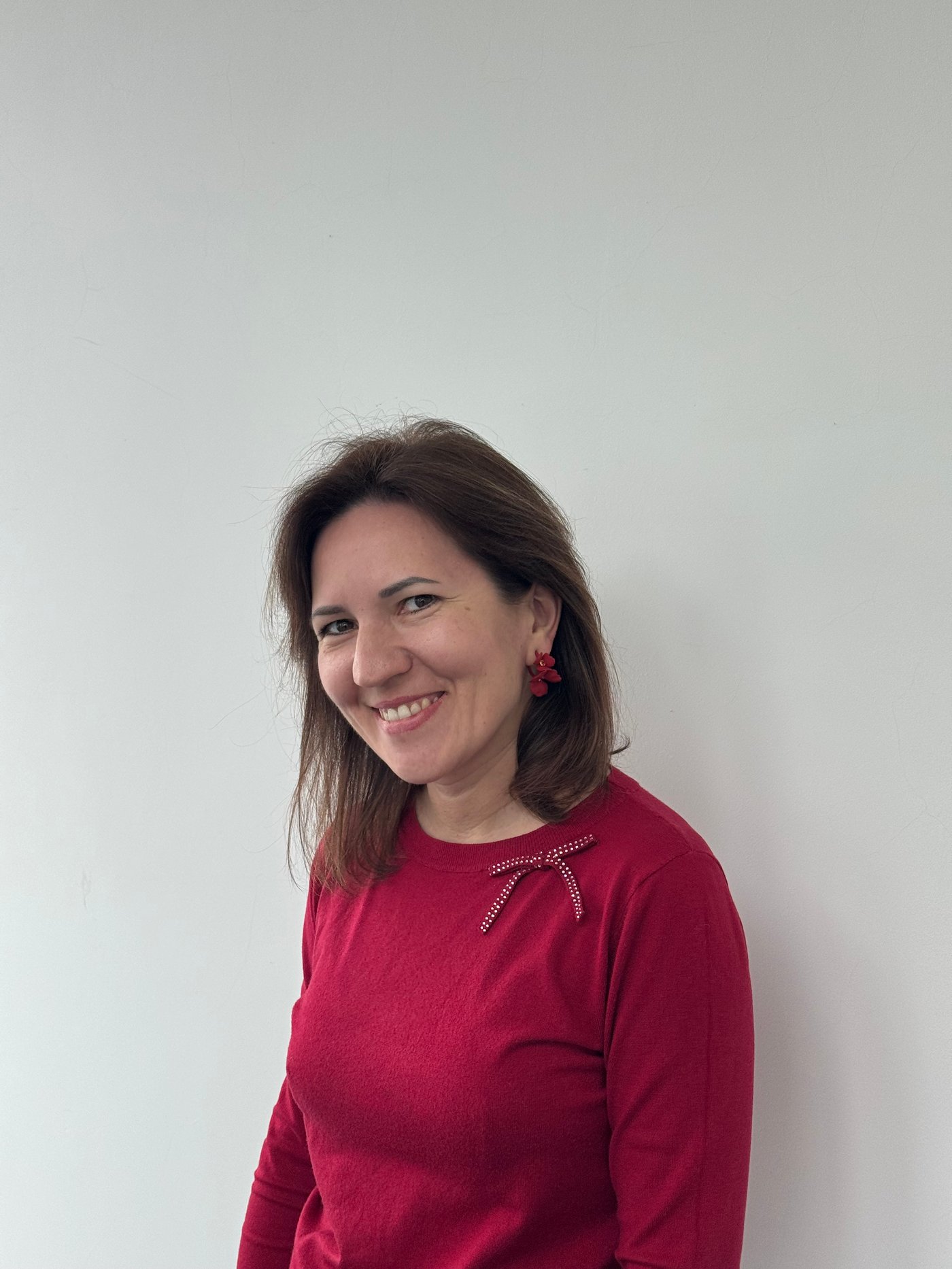 Olena portant un pull rouge et souriant à l’objectif.