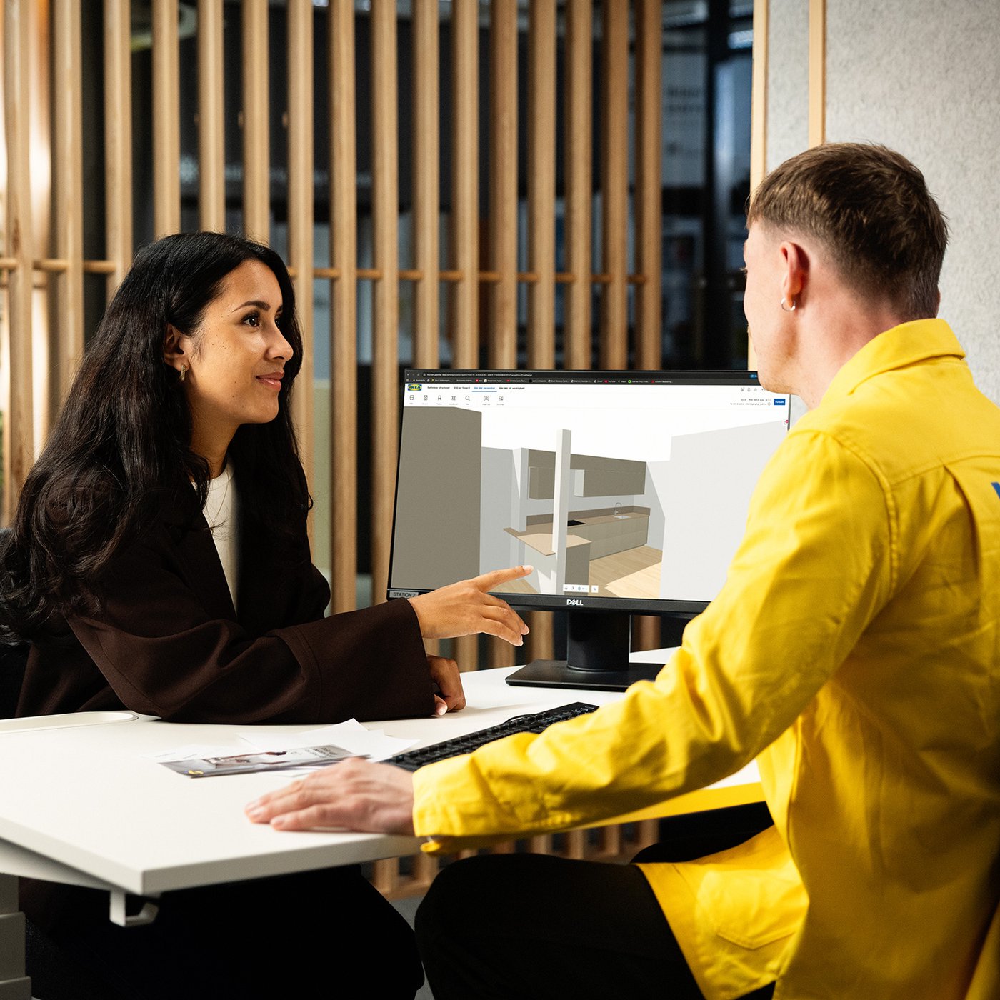 IKEA zaposleni i kupac gledaju 3D kuhinjski raspored na monitoru.