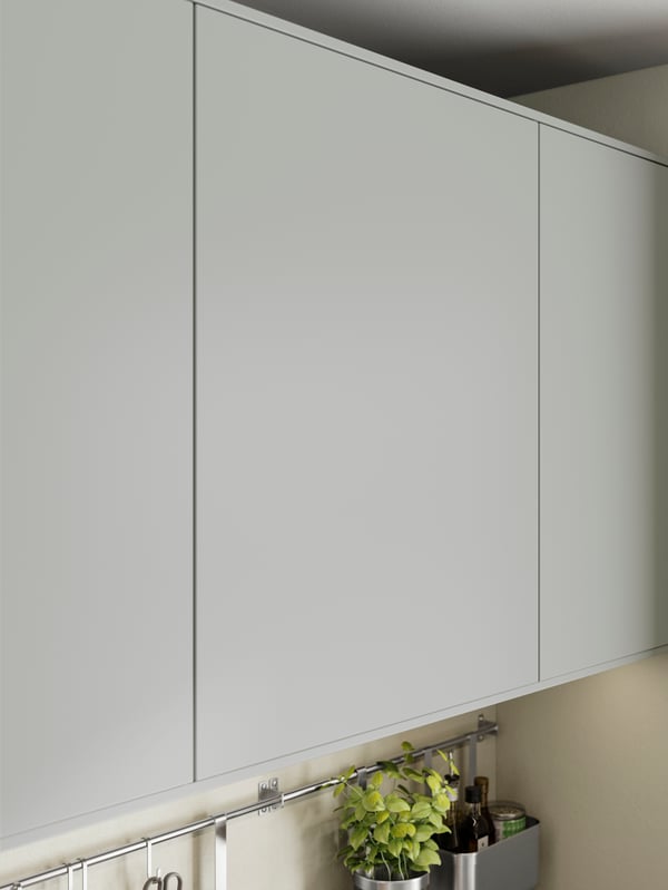 HAVSTORP light grey kitchen cabinet fronts with a potted plant and kitchen utensils organised on a rail underneath.