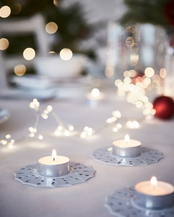 Many GLIMMA tealight candles on a table with a white tablecloth
