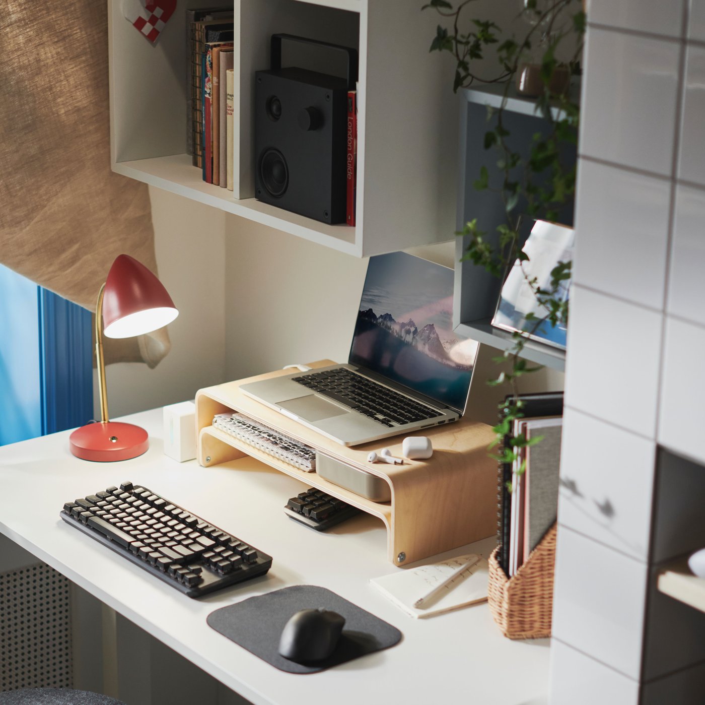 A white TROTTEN sit/stand desk has a laptop, laptop monitor stand, keyboard and mouse on top of it, by a sit/stand support.