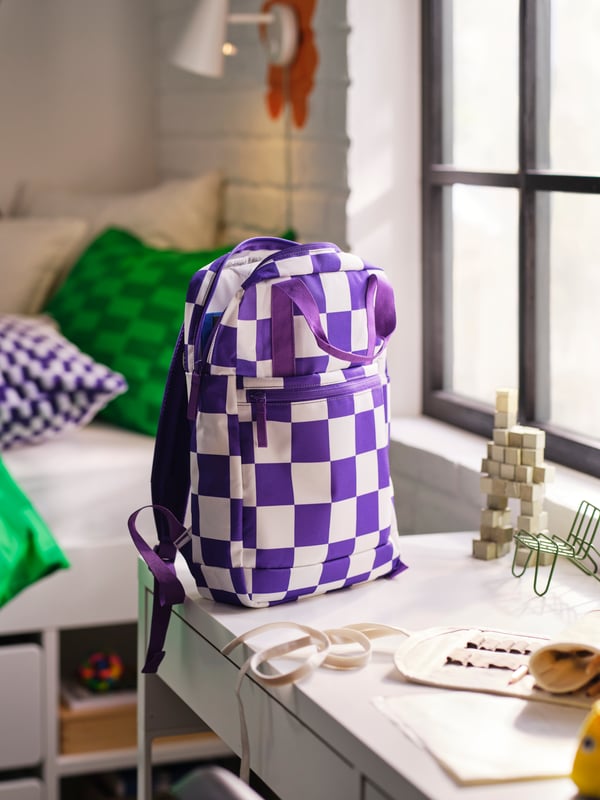 Ruimte met tal van accessoires en in het midden een tas met ruitmotief in paars en wit.