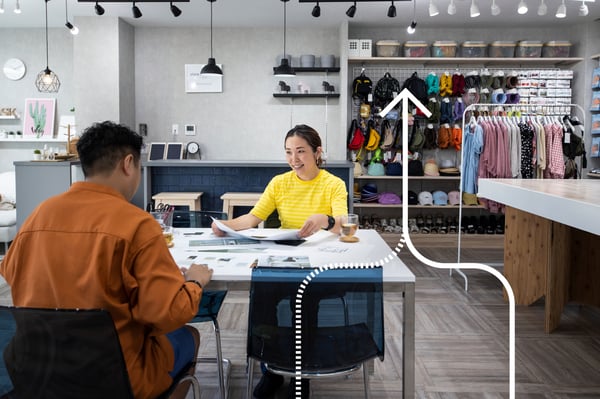 A man and an IKEA co-worker are looking over plans in his retail space. 
