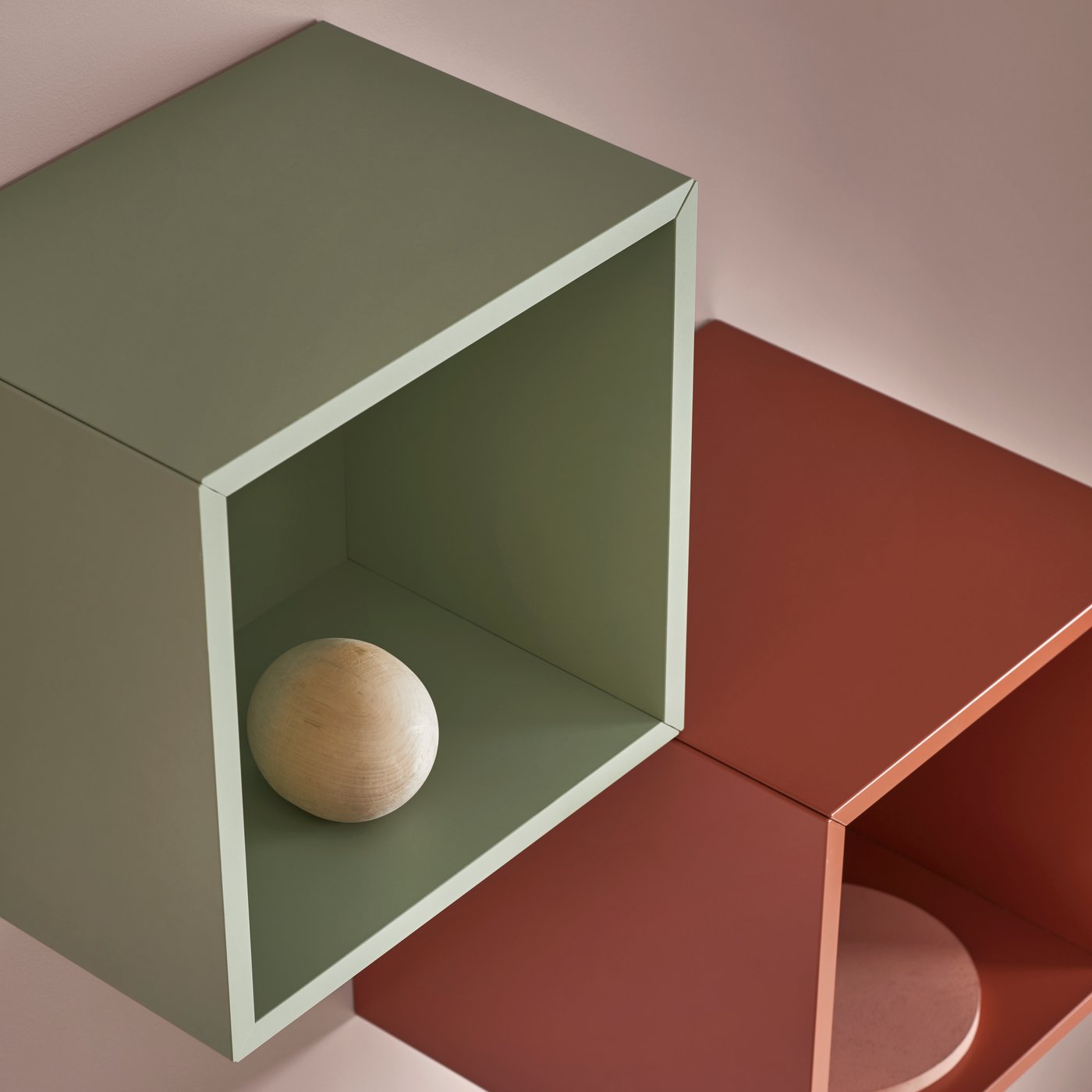 On a pink wall, there is a light green EKET and a red-brown EKET.