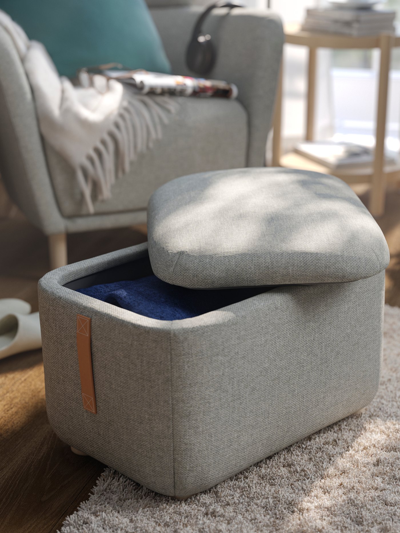 A beige-grey OSKARSHAMN footstool with storage, its lid off to reveal a textiles inside, next to its wing-chair sibling.