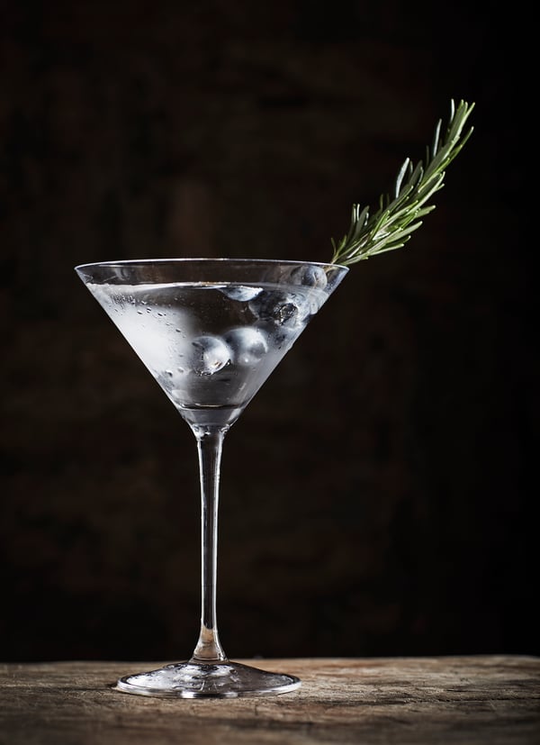 Närbild på ett cocktailglas med en dekorativ kvist i.