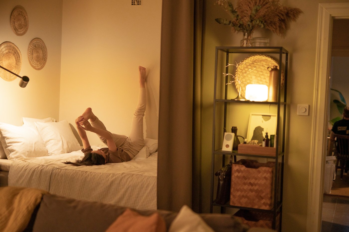 Woman stretching on the bed before bedtime, surrounded with warm yellow mood lights.