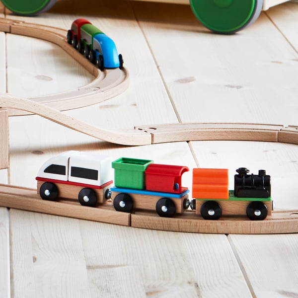 A LILLABO wooden train set sits on wooden floors with 3 carts. 