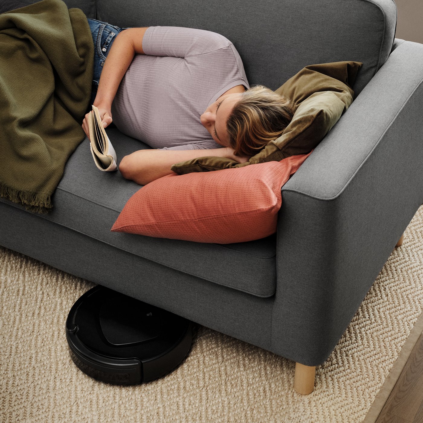 A woman lying on a PÄRUP sofa reading a book.