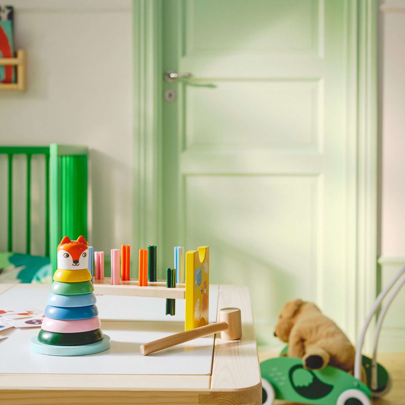 The UPPSTÅ toy hammering block and stacking rings on a table, with a crib and a toddler walker in background.