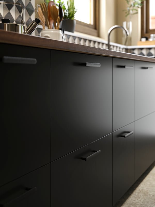 A kitchen with NICKEBO drawer fronts in matte anthracite and NYDALA handles in black and a PERSILLADE plant pot.