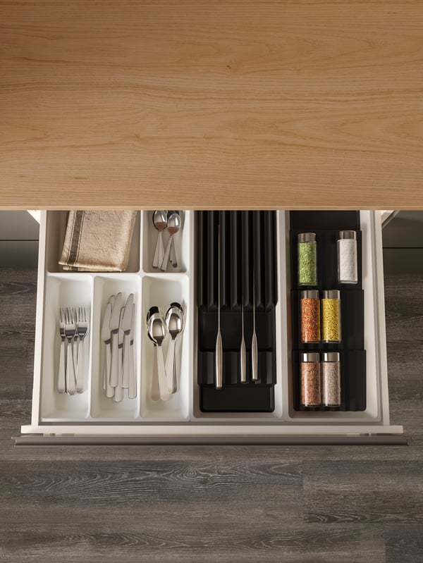 Spice jars lay on two UPPDATERA sliding organisers and cutlery