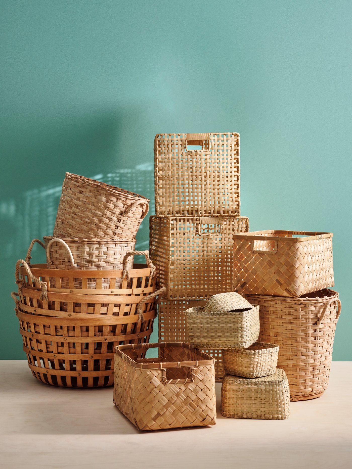 Various shapes and sizes of wicker baskets stacked on each other with a blue wall behind
