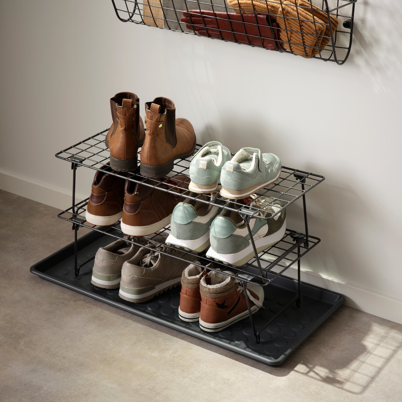 Zwei schwarze GREJIG Schuhregale mit Turnschuhen und Stiefeln im Flur.