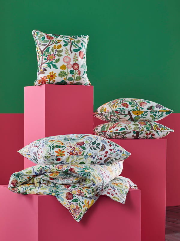 Ein buntes floral gemustertes STRANDLUMMER Bettwäsche Set mit mehreren VILSPERSILJA Kissen.