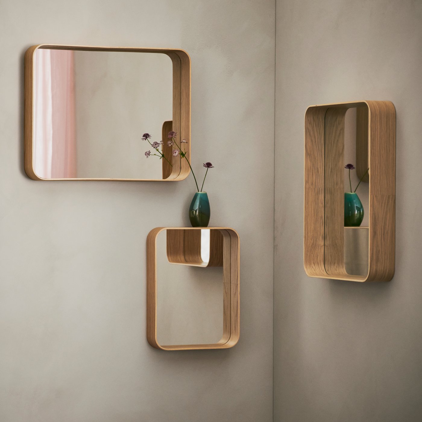 Three wall-mounted DVÄRGSYREN mirrors in different sizes and shapes. There’s a reflection of a pink curtain in one of them.