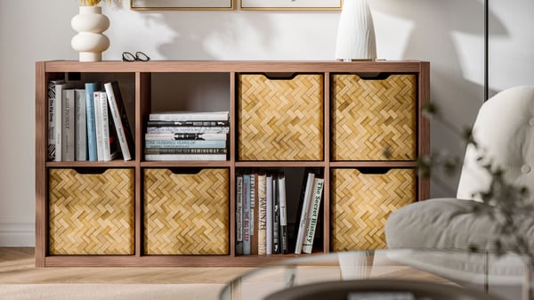 An open KALLAX wall shelf in a brown walnut effect with 8 compartments filled with baskets and books in the living room.